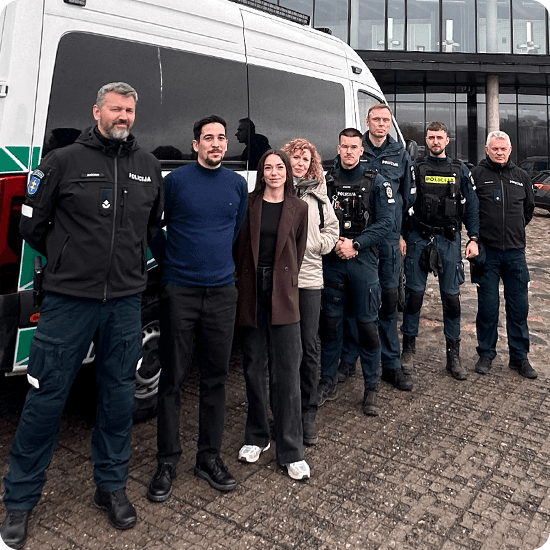 Several individuals of varying ages and backgrounds pose in front of a van, showcasing camaraderie and friendship.