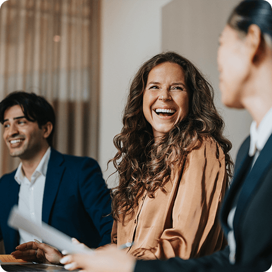  Woman laughs with two men and another woman during a meeting, creating a lively and engaging atmosphere.