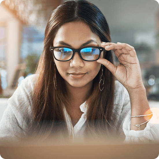 A woman with glasses, looking thoughtfully to the side, showcasing her stylish eyewear and confident demeanor.