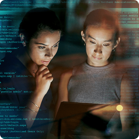 Two women engaged in discussion while looking at a computer screen together.
