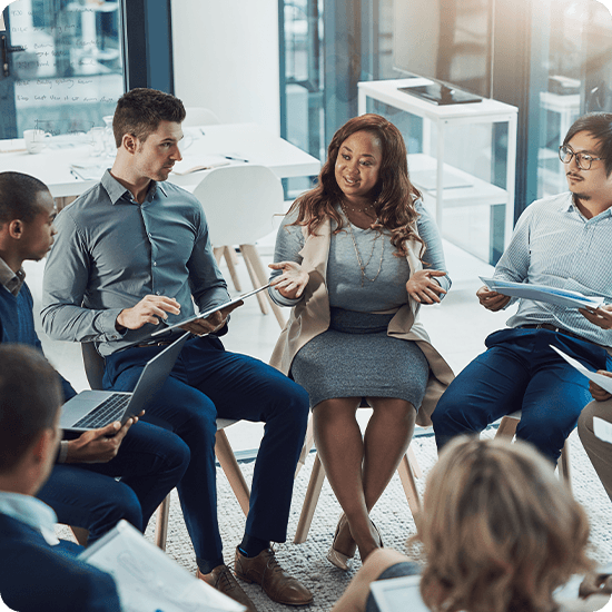 A group of five individuals seated around a table, reviewing documents and discussing ideas collaboratively.