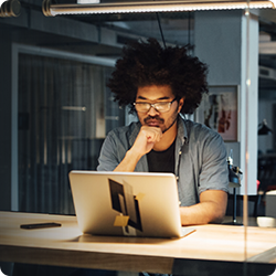 A man with glasses looking at his laptop screen