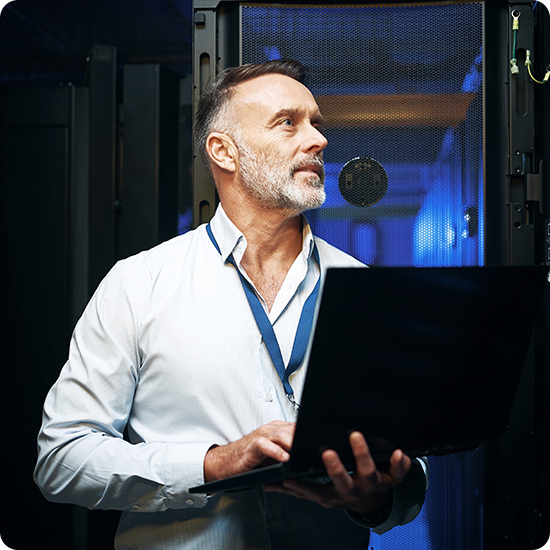 A man holding a laptop and looking at a server