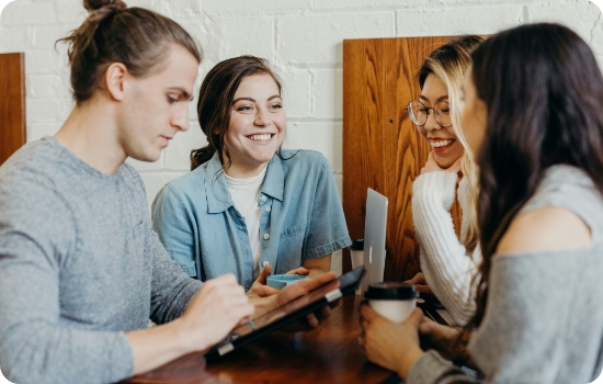 A group of young people talking over laptops
