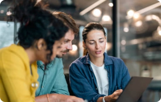 3 people talking and looking at a laptop
