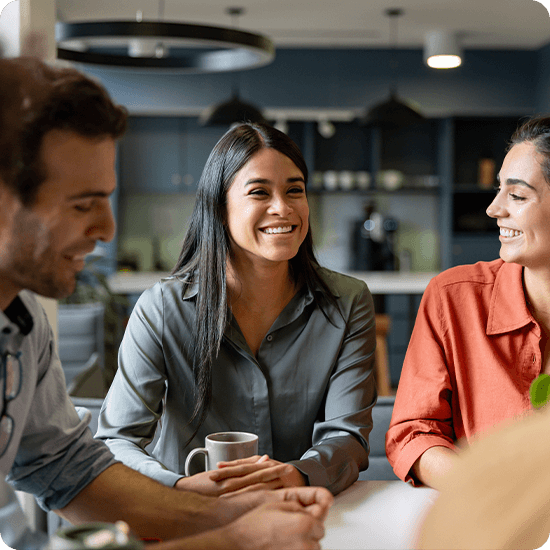 Three people engaged in conversation while seated at a table, sharing ideas and enjoying each other's company.
