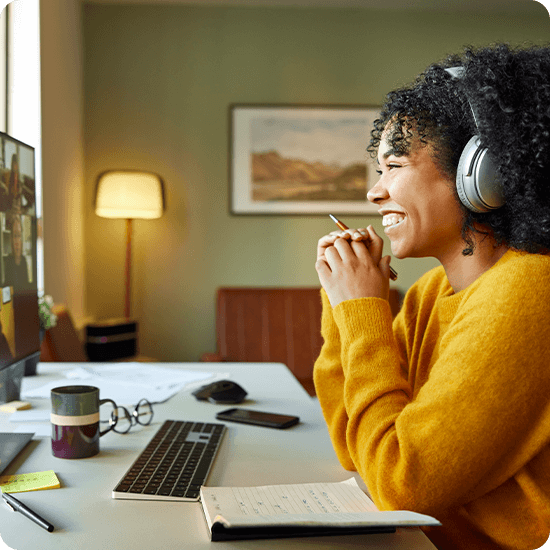 Woman with headphones on smiling at a monitor