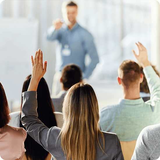A person lecturing and several people with their hands raised