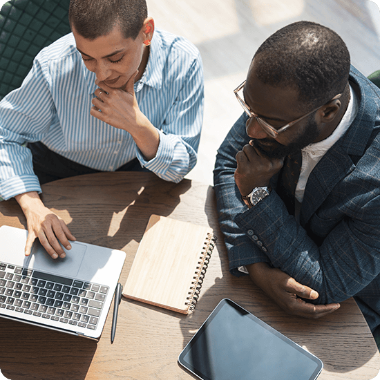 Two men working over a laptop