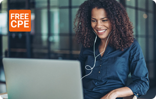 A woman wearing wired ear phones looking at her laptop