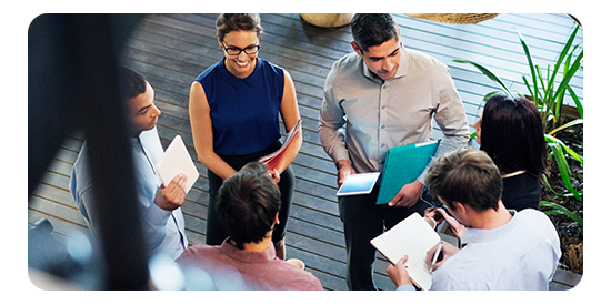 Employees holding documents and huddled in a circle