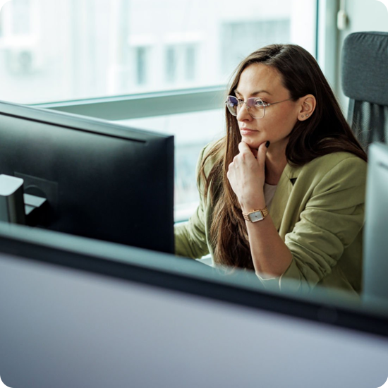 A woman sitting at a desk looking at her monitor