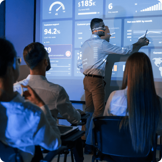 Students in a classroom with and instructor at a digital board