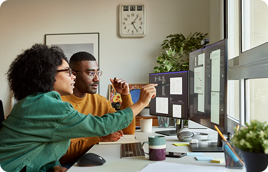 Two employees looking at a desktop monitor