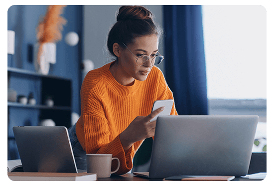 Woman in front of two laptops and a phone