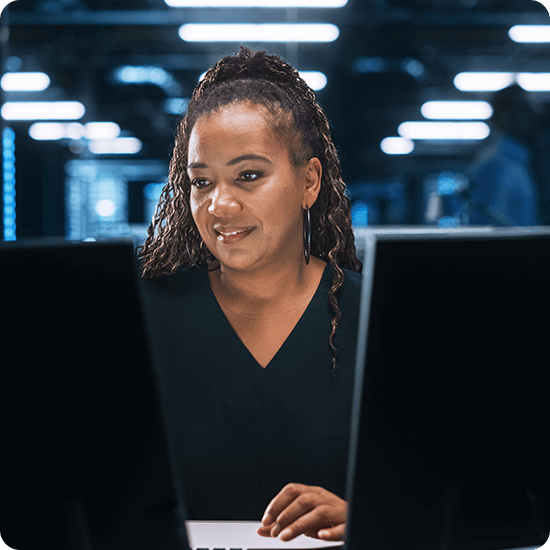 A woman working in front of two monitors